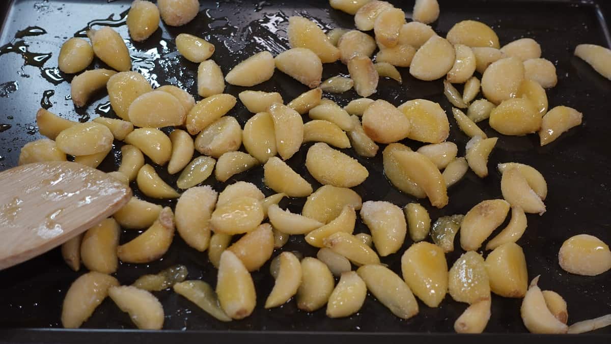 Garlic cloves on a baking sheet with oil and salt.
