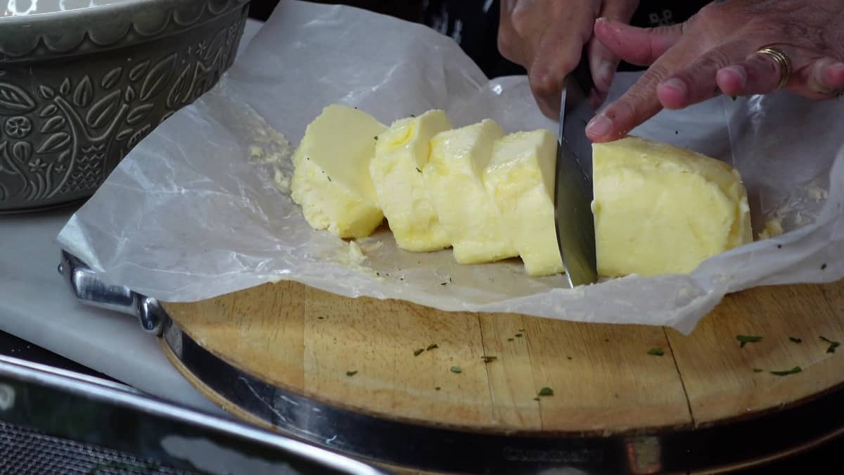 A knife cutting a large chunk of butter into pieces.