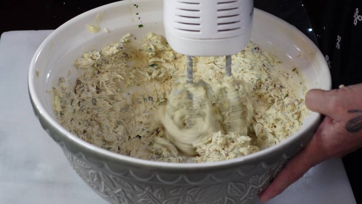 A hand mixer and a bowl mixing compound butter.
