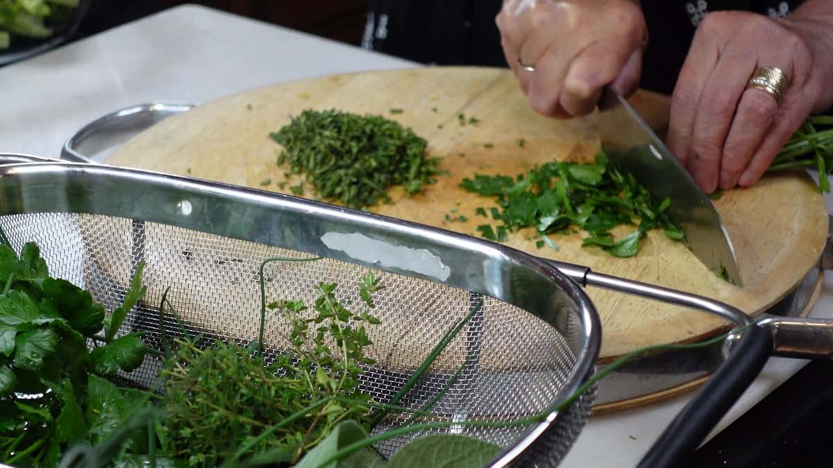 Fresh herbs being chopped to make an herb compound butter.