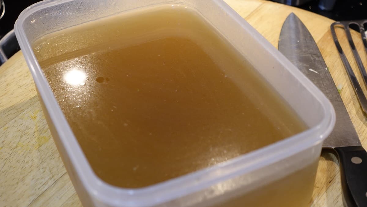 A plastic container with homemade turkey stock.