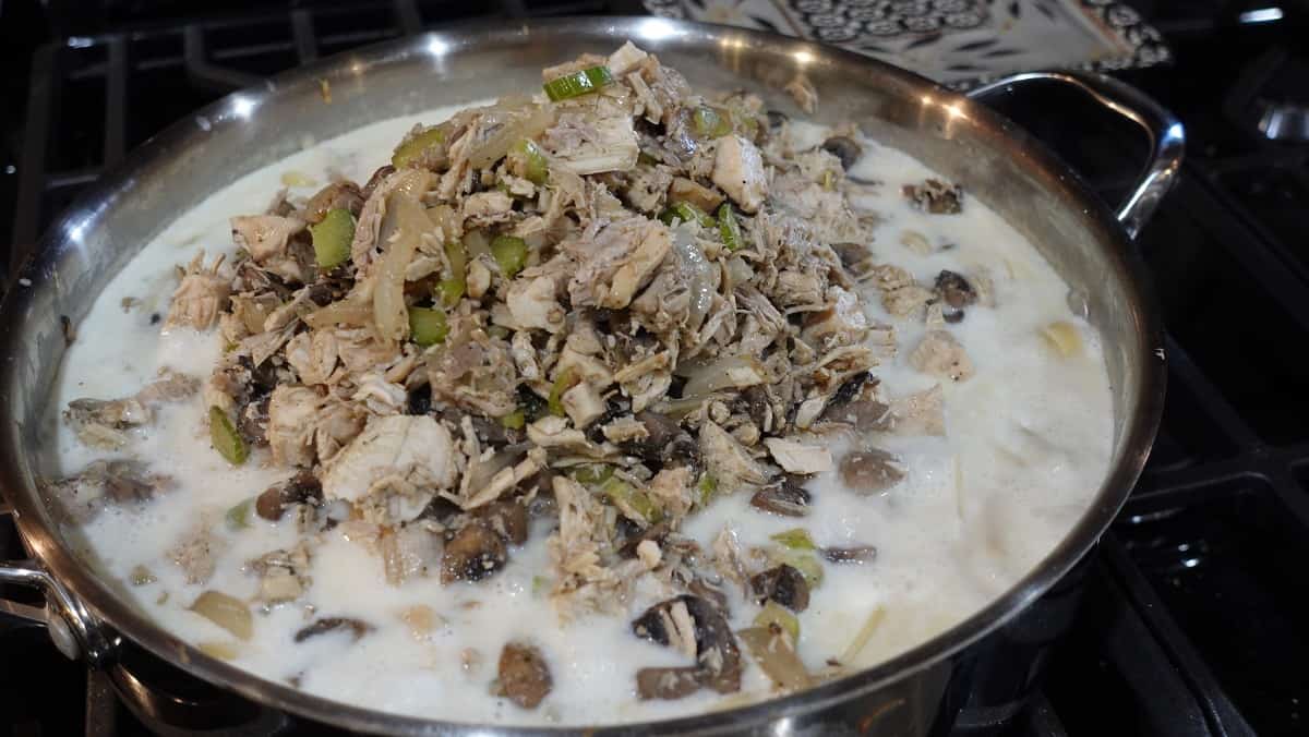 Turkey and mushrooms being added to a skillet for making Leftover Turkey and Linguine Casserole.