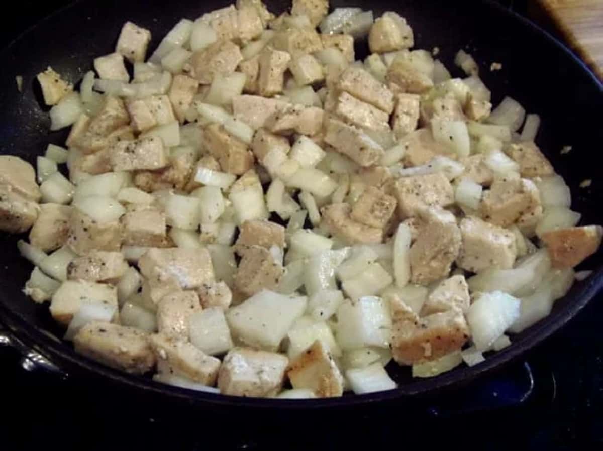 Chicken and onion in a skillet.