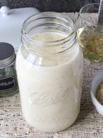 A mason jar filled with Homemade White Wine Alfredo Sauce.