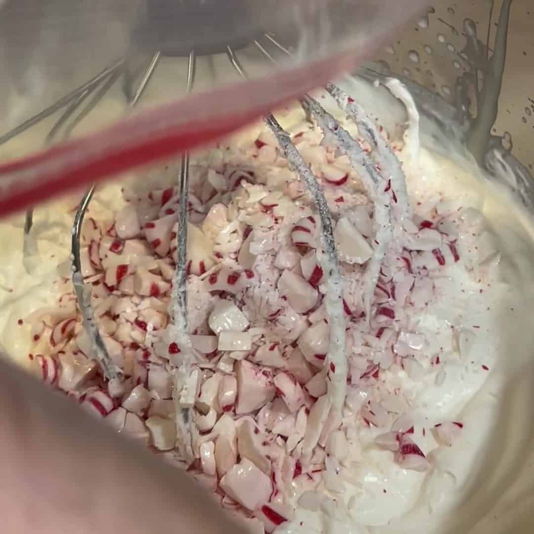 Crushed peppermint candy being added to no-churn peppermint ice cream.