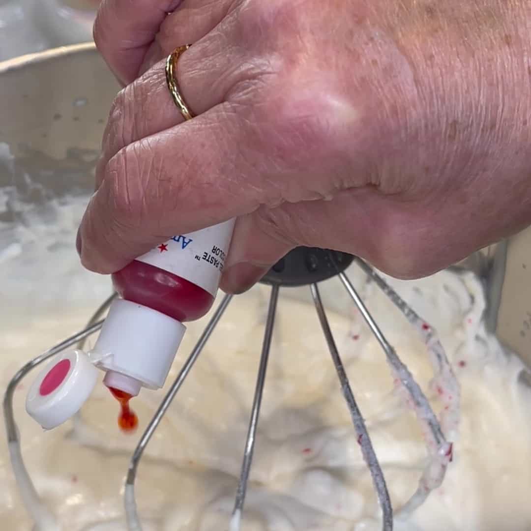 Pink food coloring being added to a no churn peppermint ice cream.