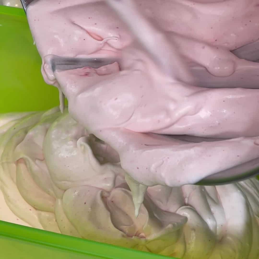 Soft ice cream being spooned into a green ice cream container.