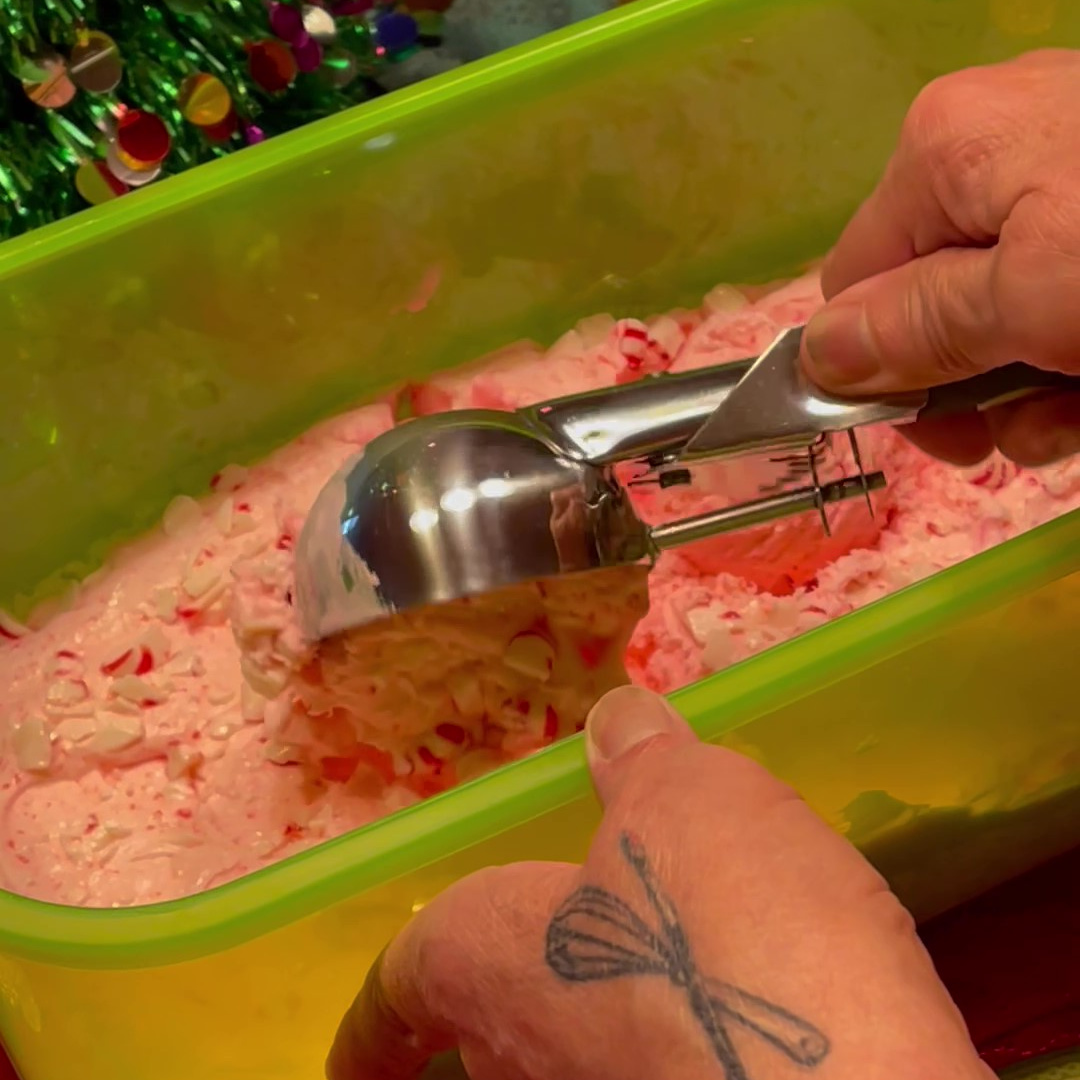 An ice cream scoop scooping No-Churn Peppermint Schnapps Ice cream.