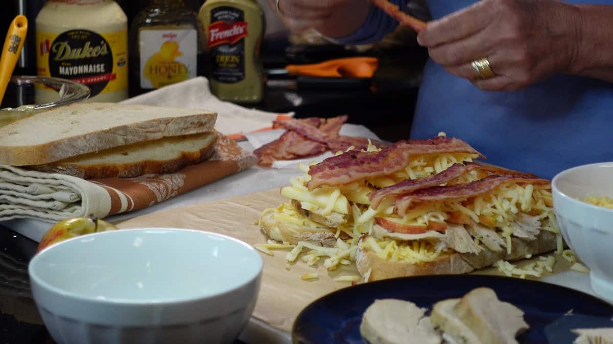 Bacon slices being added to a sandwich.