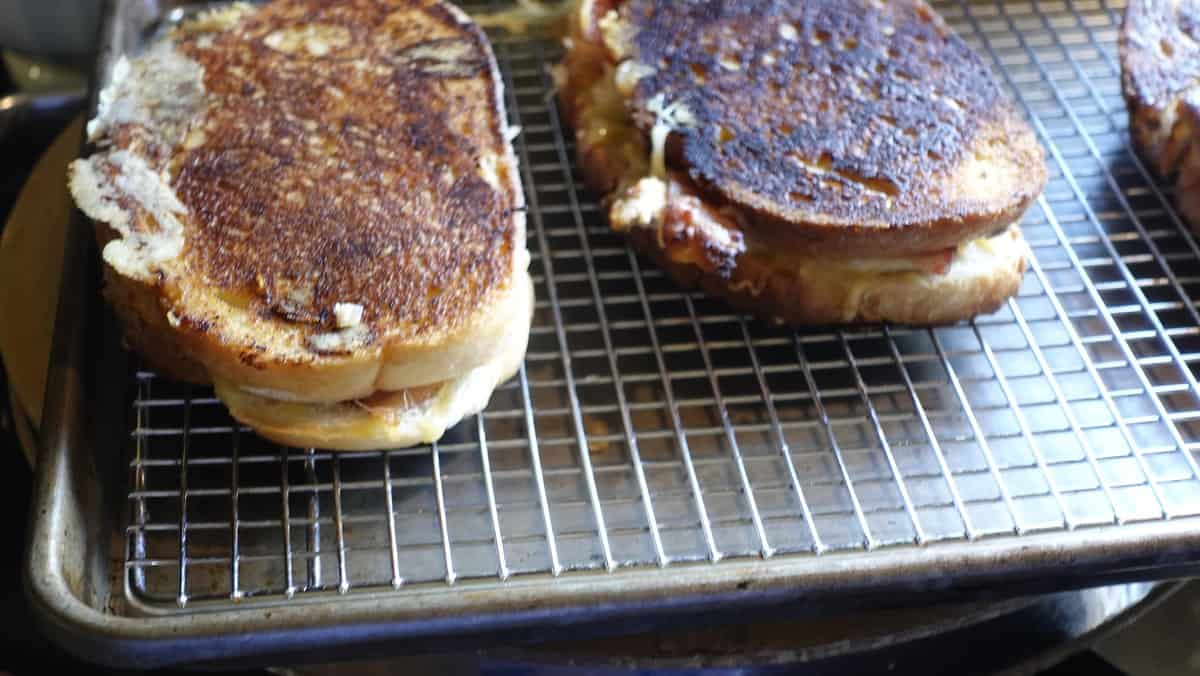 Two Turkey and Smoked Gouda Grilled Cheese Sandwiches on a wire rack.