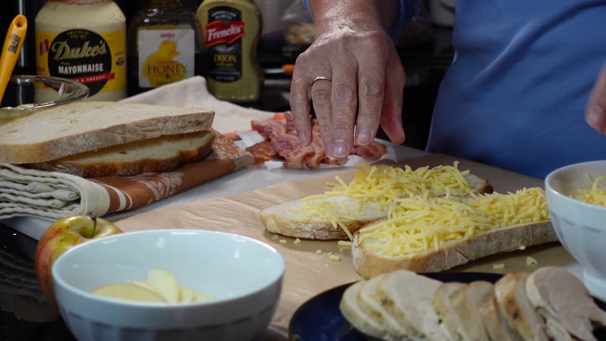 Shredded cheese being added to a grilled cheese sandwich before cooking.