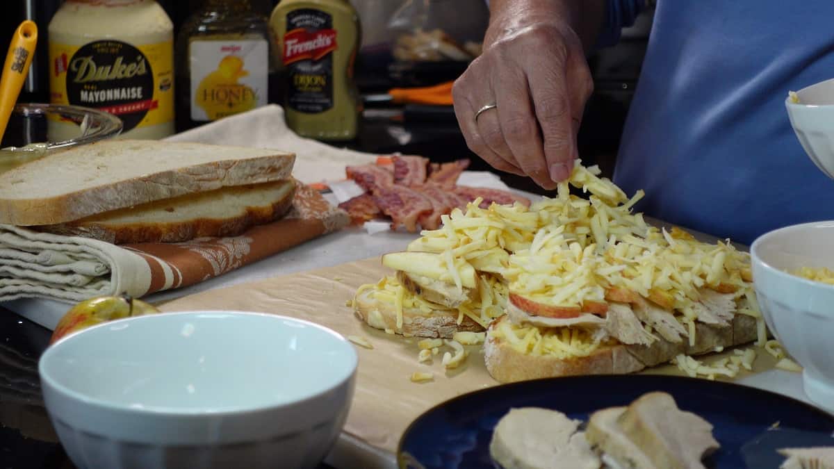 Shredded cheese being added to a grilled cheese sandwich before cooking.