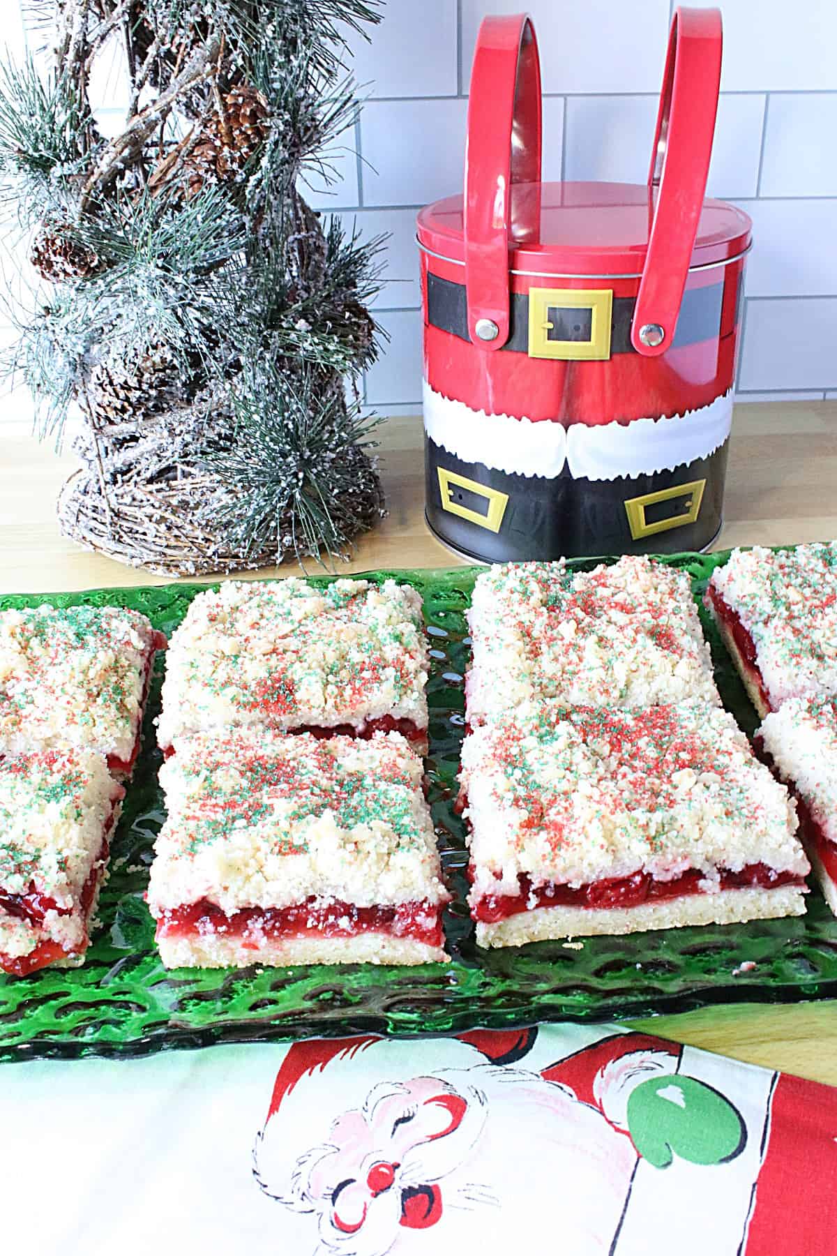 A cute Santa tin with a glass plate filled with Kringle Kuchen in the foreground.