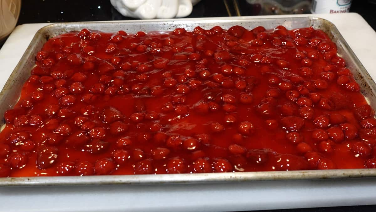 Cherry pie filling spread over a crust on a baking sheet.