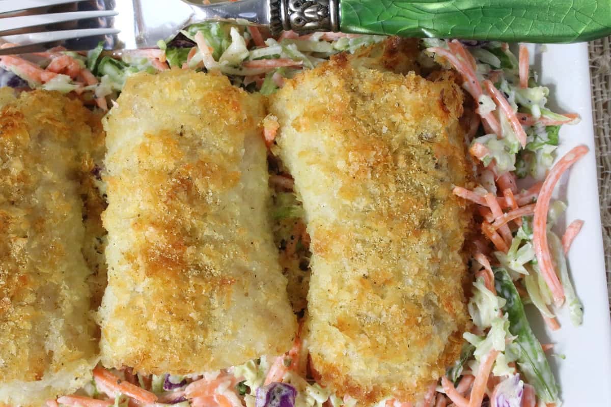 Overhead photo of three golden potato crusted cod fillets on a white platter.