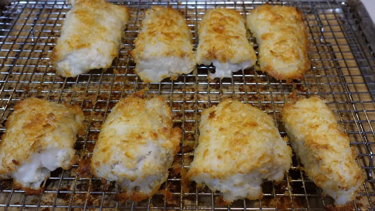 Eight pieces of cooked and golden Potato Crusted Cod on an oven rack.