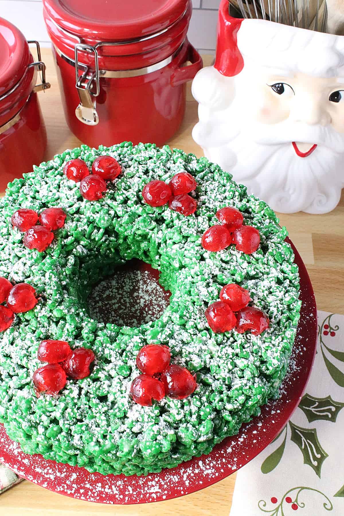 Adorable Rice Krispies Christmas Wreath treat with red cherries and powdered sugar.