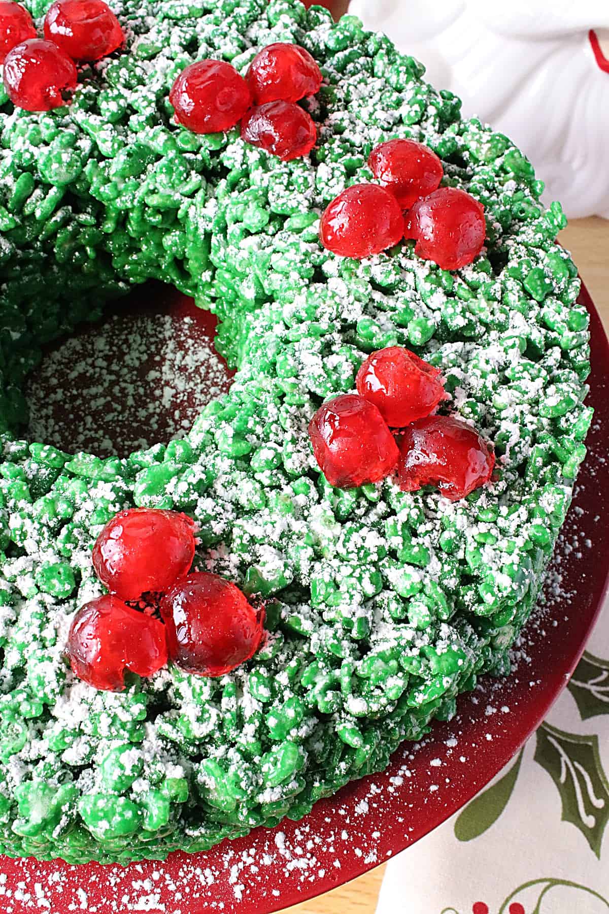 Red candied cherries on top of a green Rice Krispies Christmas Wreath.
