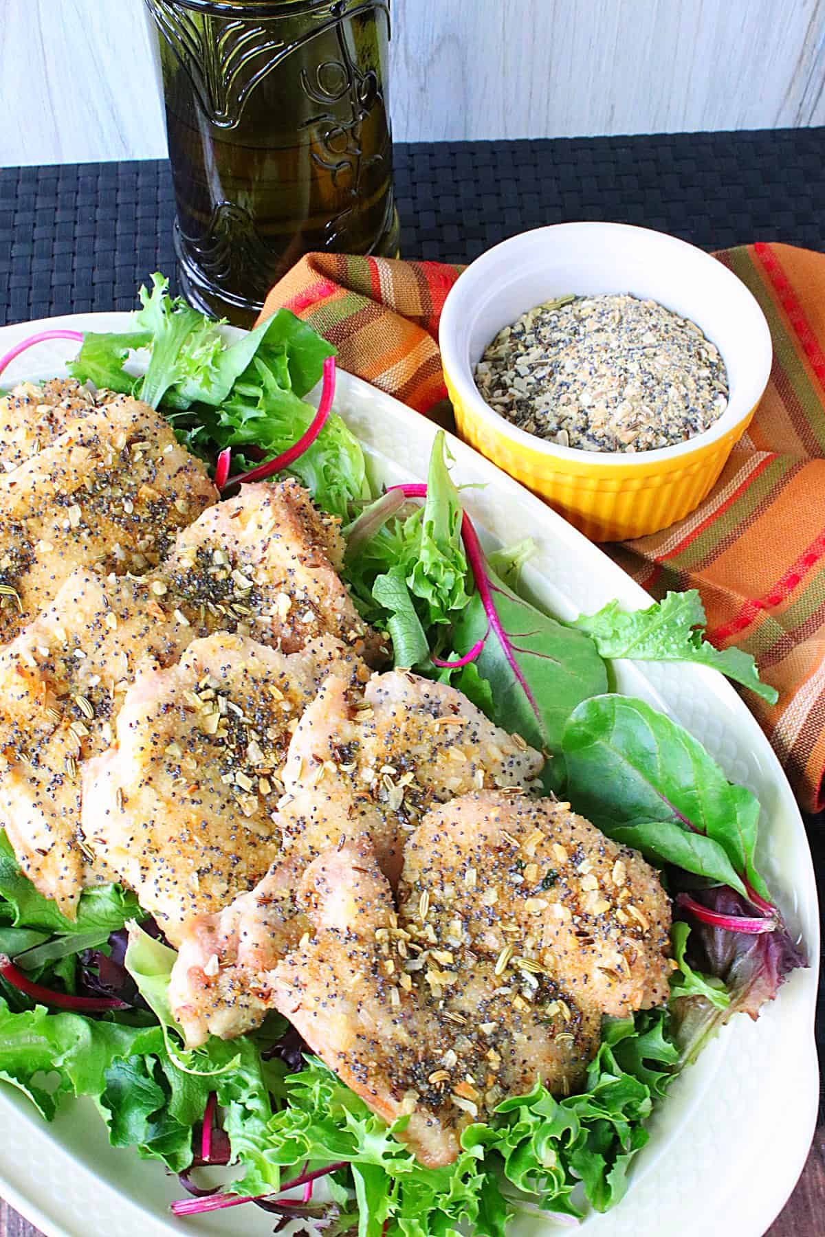 A platter of Everything Seasoned Chicken Thighs with a small bowl of seasoning in the side.
