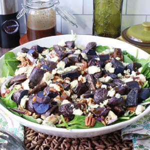 A beautiful bowl of spinach salad with purple potatoes, pecans, blue cheese, and sliced onions.