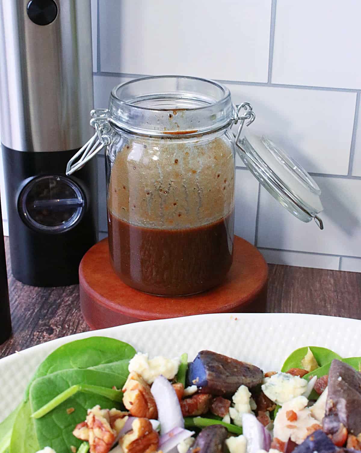 A glass jar with a lid containing a poppy seed balsamic vinaigrette.