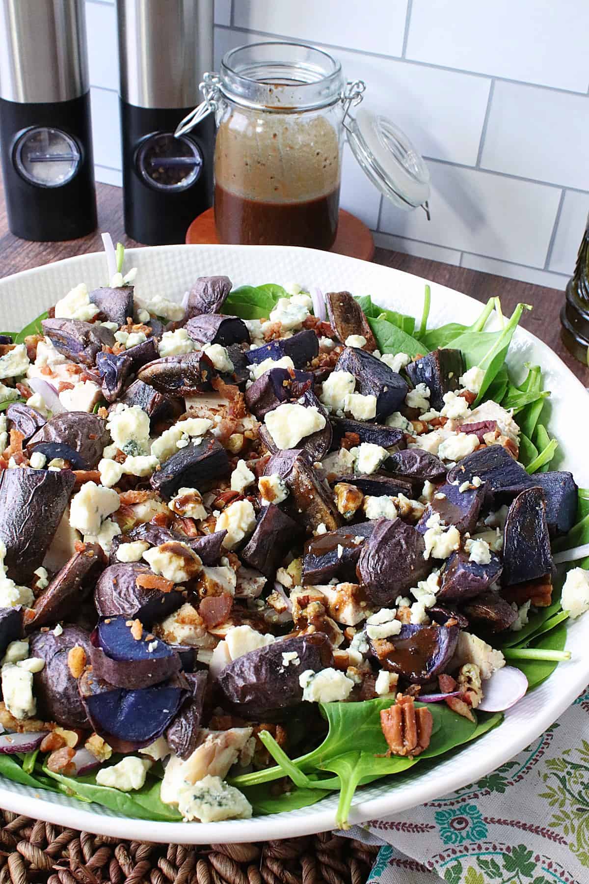Green spinach, purple potatoes, brown pecans, and white blue cheese in a salad bowl.