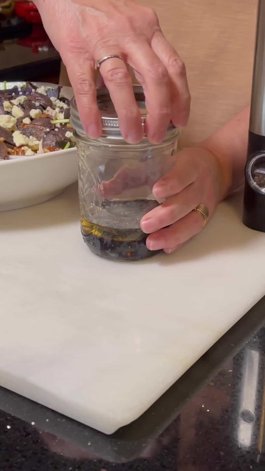 A lid being added to a mason jar with homemade vinaigrette.
