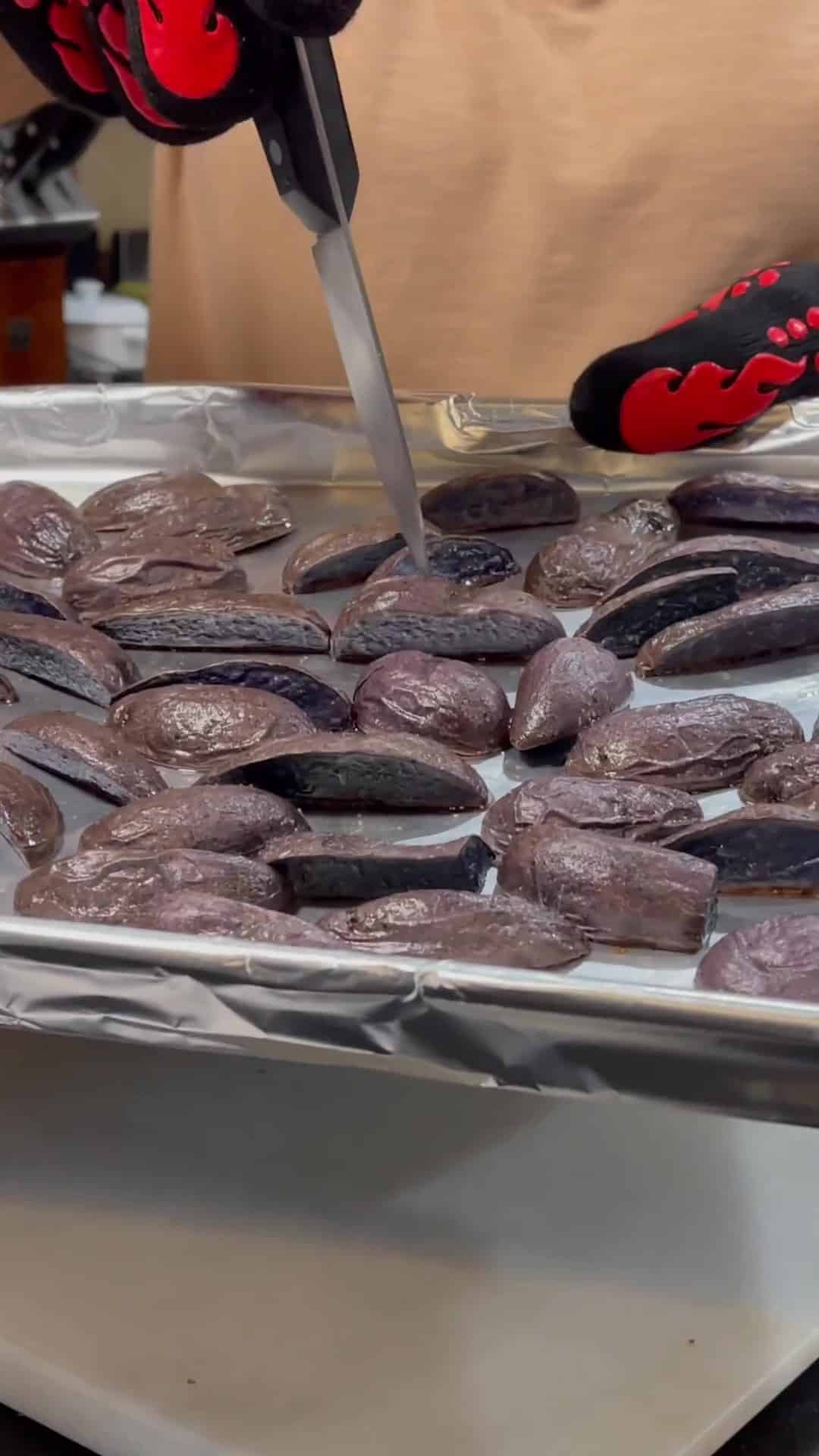 A knife being pierced into a cooked purple potato.