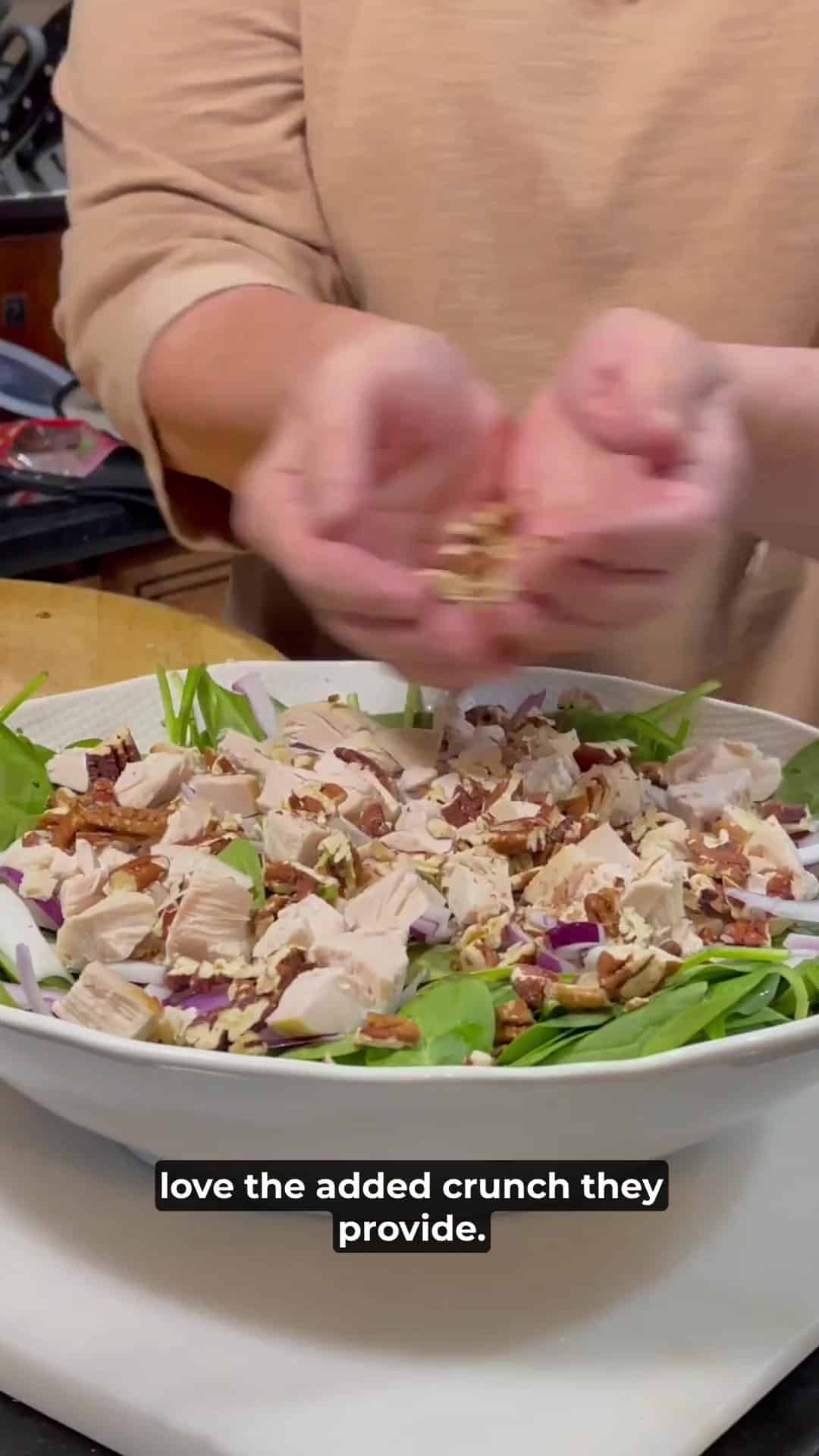 Chopped pecans being added to a Spinach Salad.