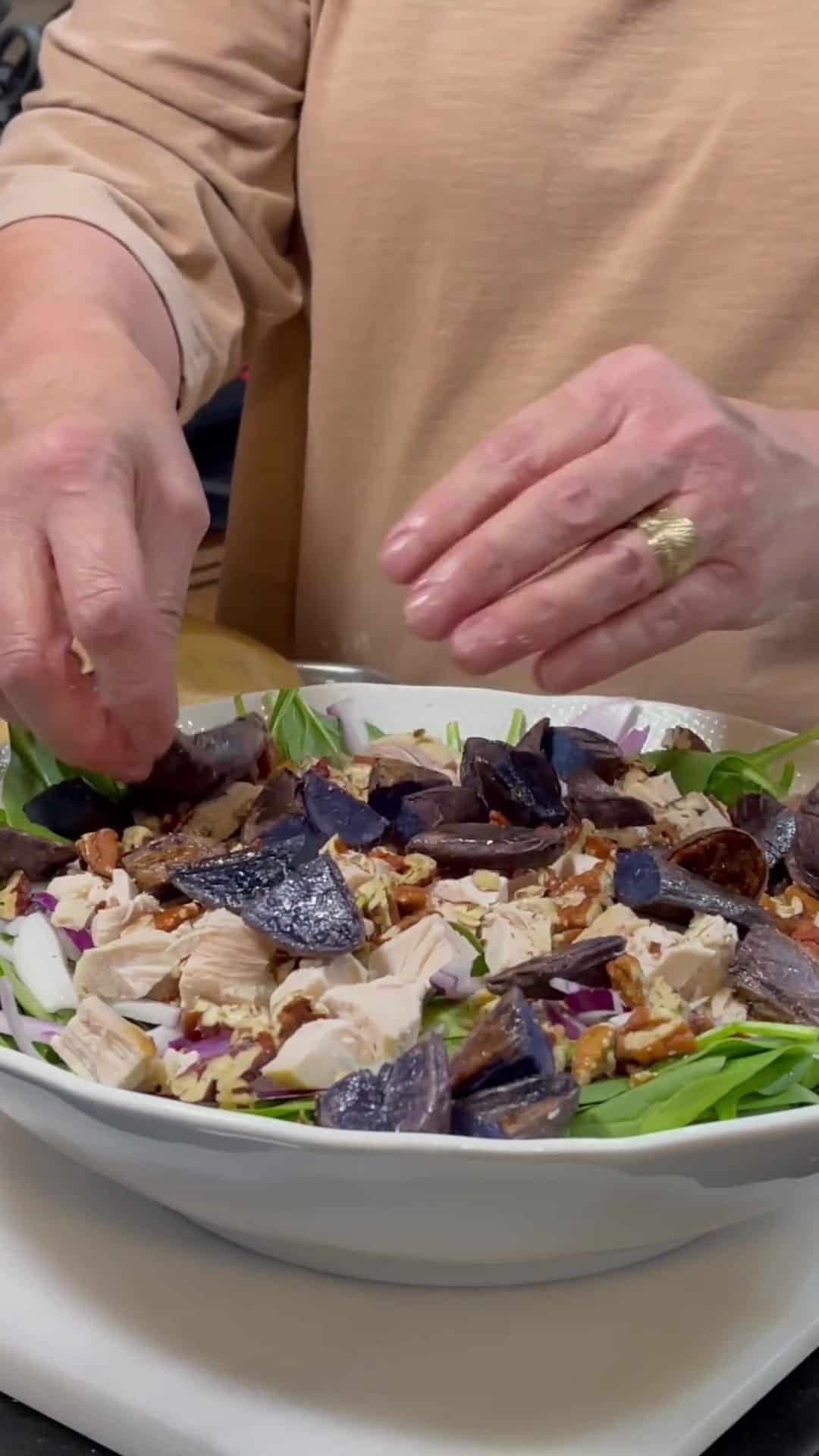 Chopped, cooked purple potatoes being added to a Spinach Salad with Blue Cheese and Purple Potatoes.