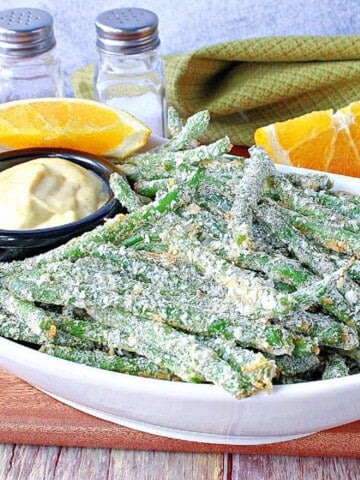 A white bowl filled with crispy potato flake Everything Green Bean Fries with orange dipping sauce.