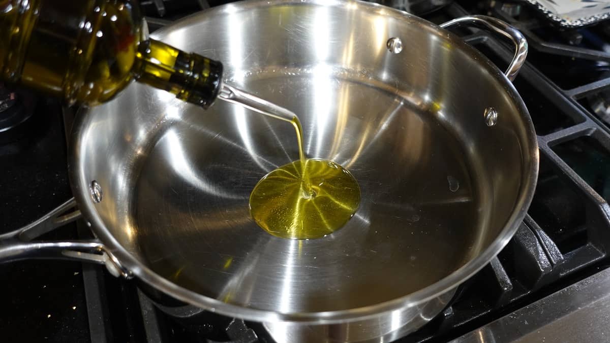 Olive oil being added to a large skillet.