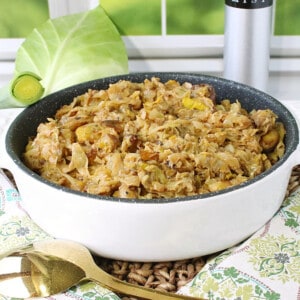 Fried cabbage and leek colcannon in a white baking dish with a gold spoon.