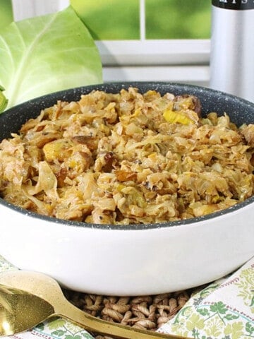 Fried cabbage and leek colcannon in a white baking dish with a gold spoon.