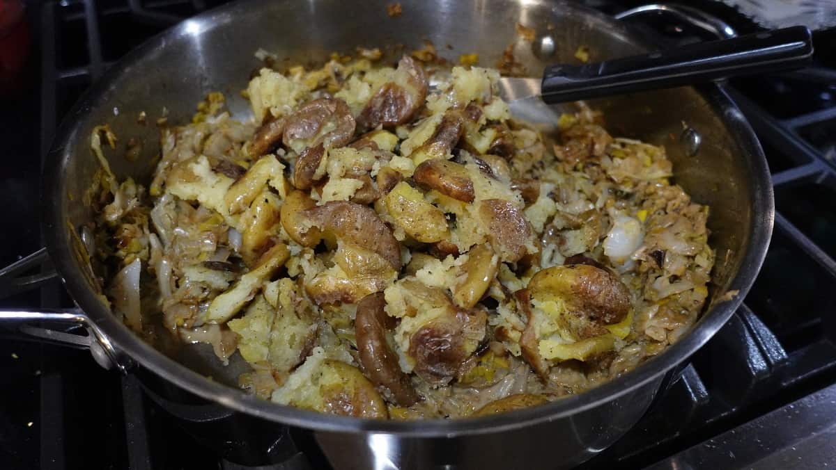 Golden brown roasted smashed potatoes added to a large skillet with cabbage and leeks.