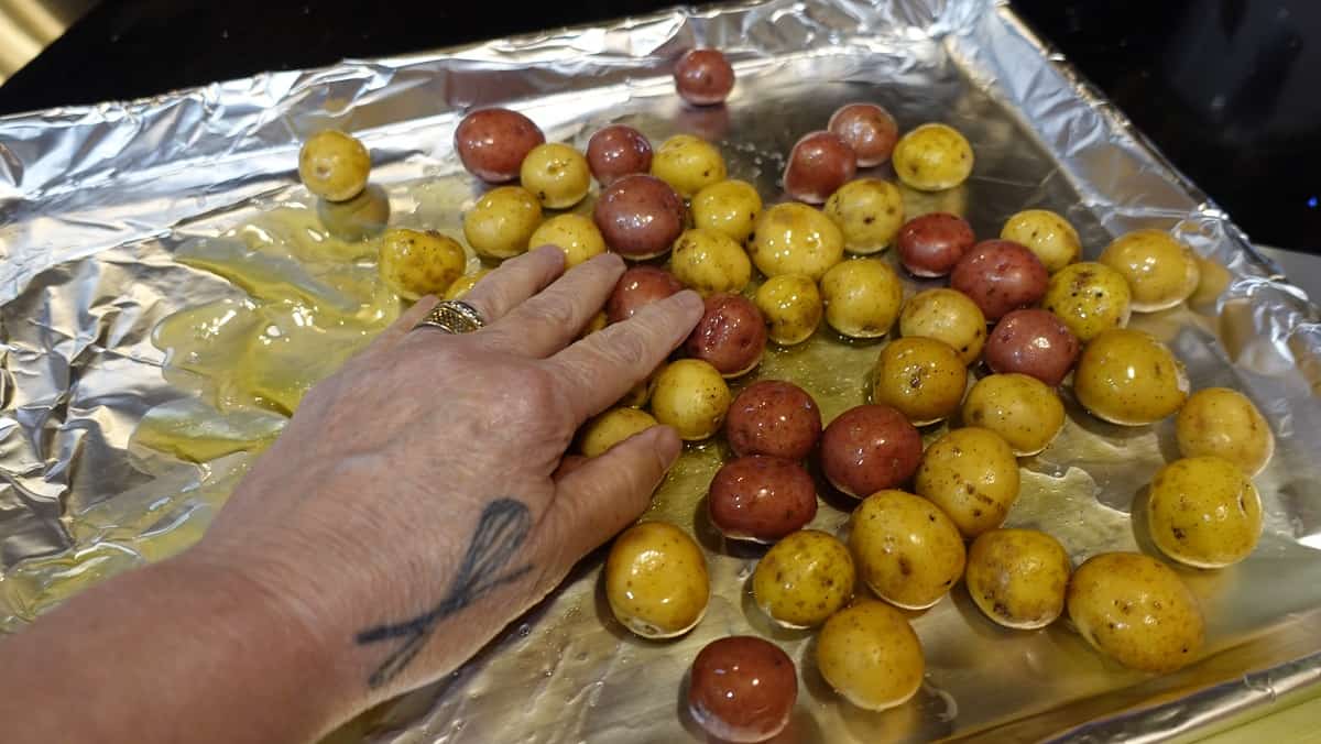 Image of baby potatoes on a baking sheet with oil.