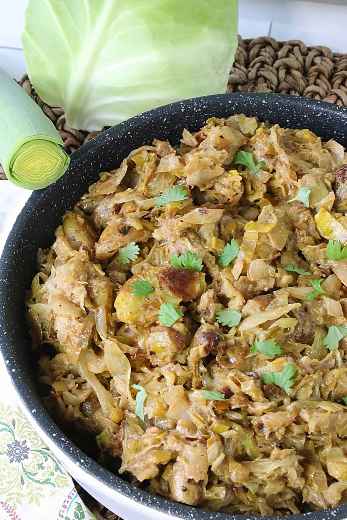 Delicious Fried Cabbage and Leeks with Roasted Smashed Potatoes in a white dish garnished with parsley.