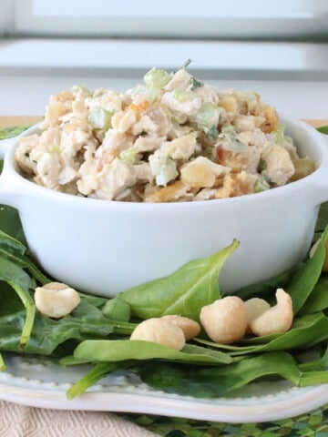 Fresh spinach leaves with macadamia nuts surrounding some Hawaiian Chicken Salad.