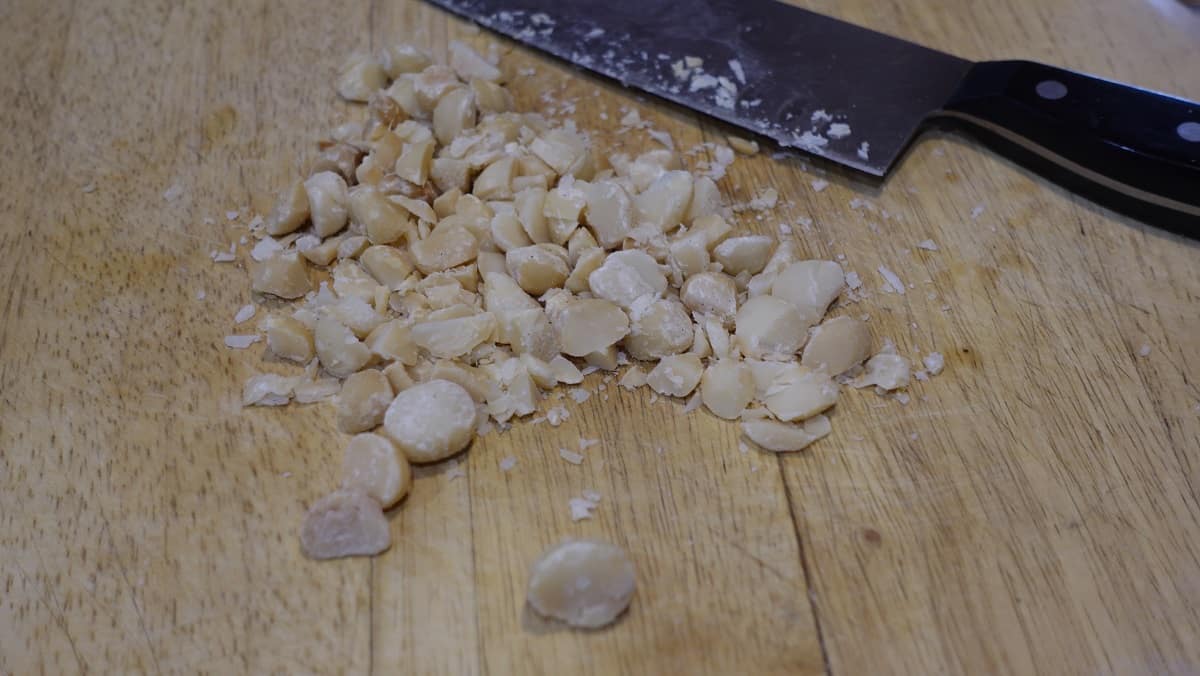 Chopped macadamia nuts on a cutting board.