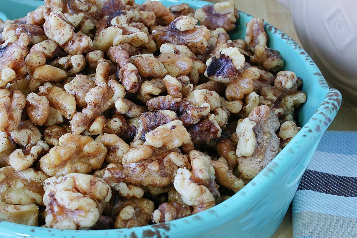 A closeup image of Cinnamon Roasted Walnuts in a blue bowl.