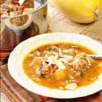 A white bowl filled with Spaghetti Squash Soup with a spoon.