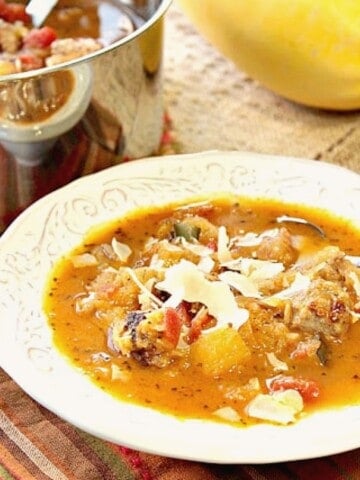 A white bowl filled with Spaghetti Squash Soup with a spoon.