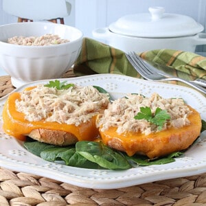 An open face Bagel Tuna Melt on a white plate.