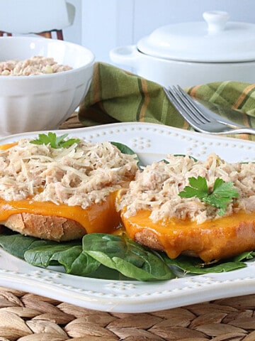 An open face Bagel Tuna Melt on a white plate.