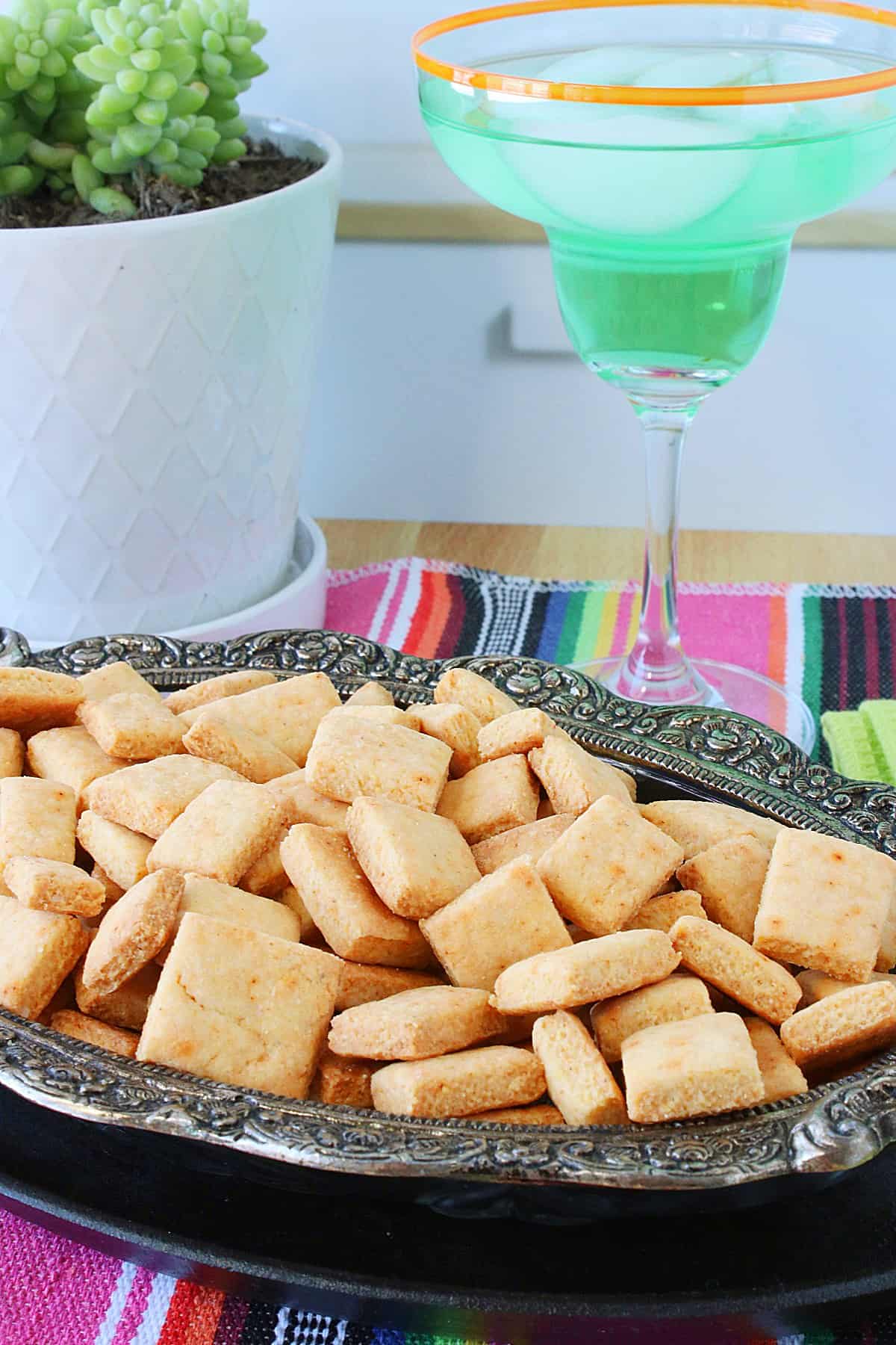 Cornbread Crackers in a pretty oval dish with a margarita glass in the background.