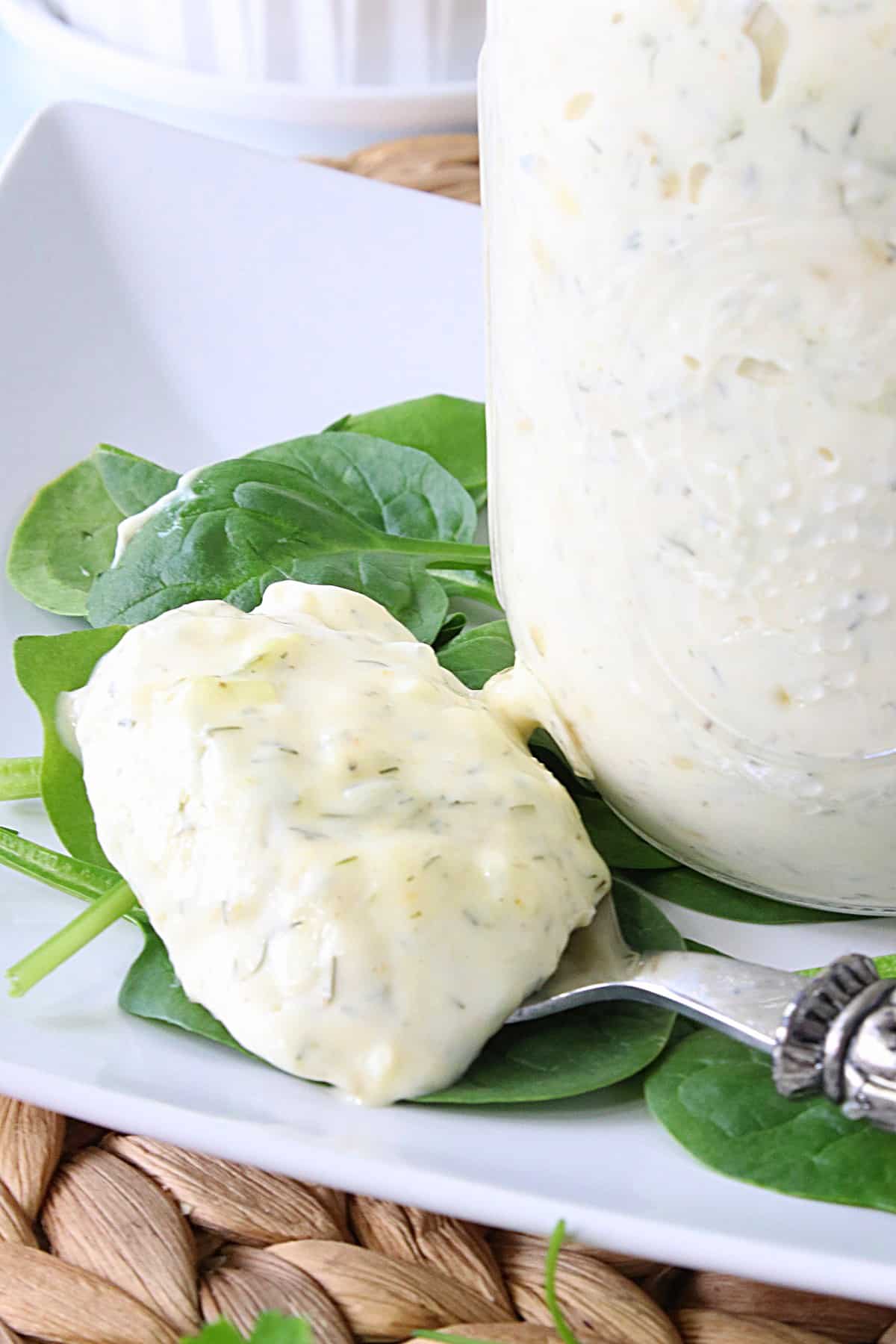 A spoon loaded with a large dollop of Homemade Dill Tartar Sauce on a white plate.