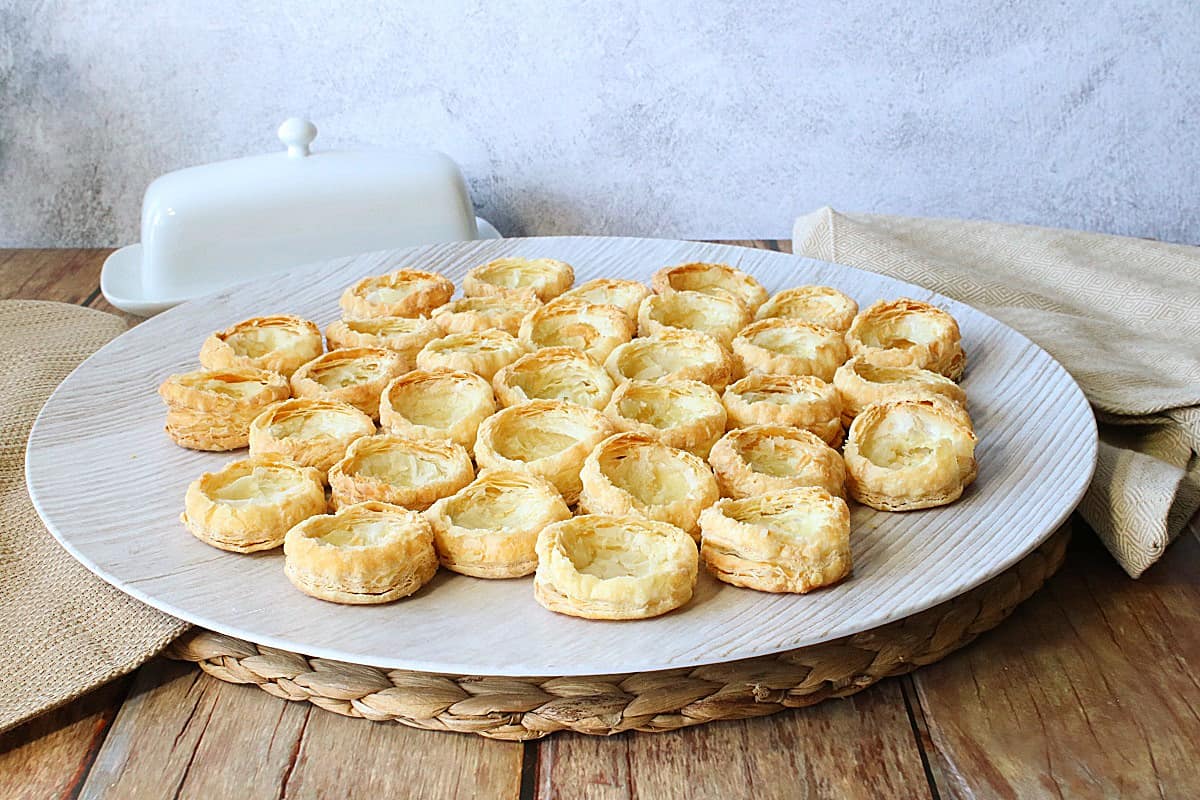 A serving plate filled with round baked Puff Pastry Appetizer Cups ready to be filled.