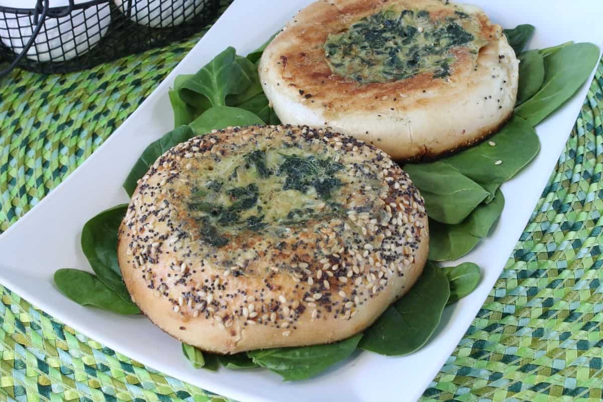 An everything bagel filled with a spinach and artichoke quiche in the hole center.
