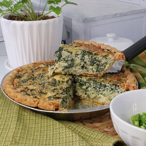 A slice of a Spinach and Artichoke Quiche sitting on top of the pie.