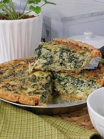 A slice of a Spinach and Artichoke Quiche sitting on top of the pie.